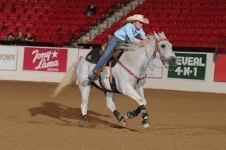 A rider on a white horse galloping during a competition