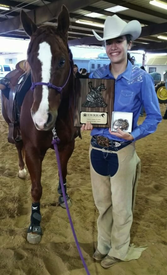 A horse next to its rider holding an award