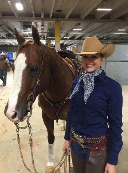 Woman standing next to her horse in the stables