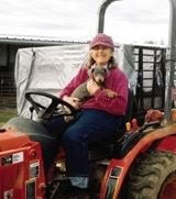 A woman holding a puppy on a tractor