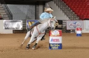a white horse turning around a barrel in an arena