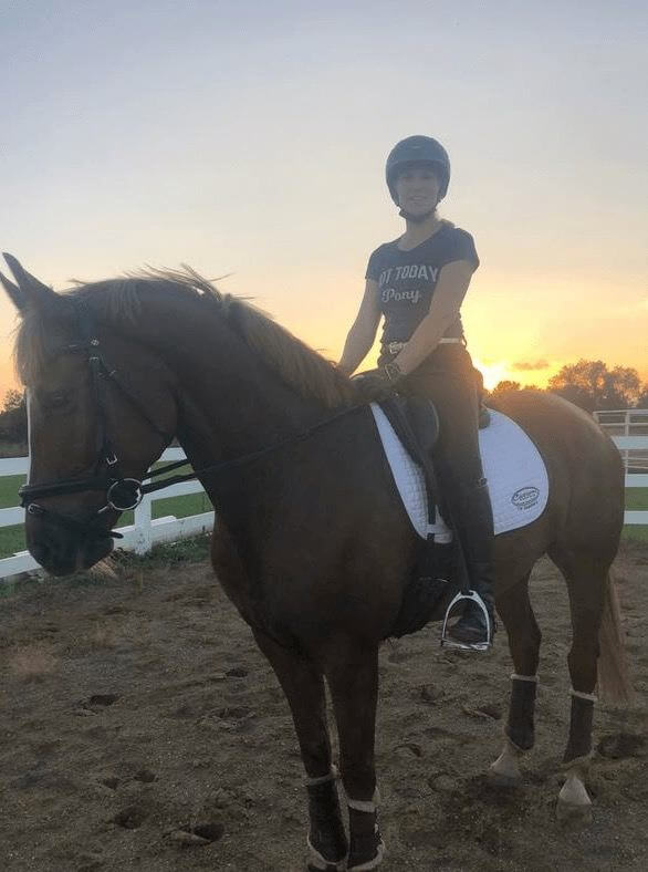 A woman riding a brown horse at sunset
